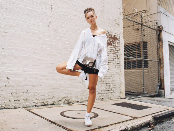 American woman mixing athleisure apparel with street style in black running shorts and Nike sneakers with high-end top and accessories