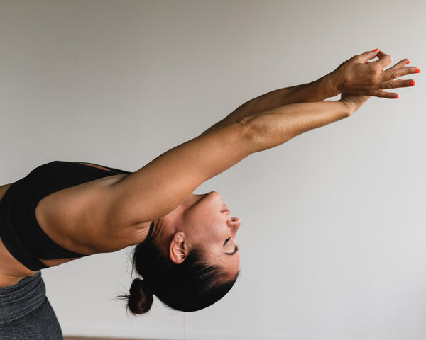 Woman stretches in all-black sports bra