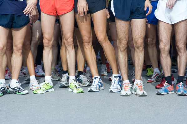 Group of people stand together wearing short running shorts