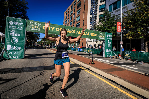 Woman wearing blue running shorts crosses finish line of marathon