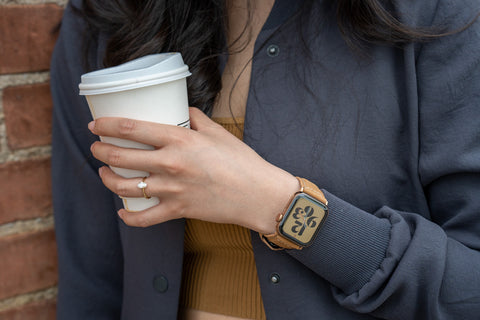Mila brown suede Apple Watch strap from Buckle and Band on the arm of a woman holding a coffee cup