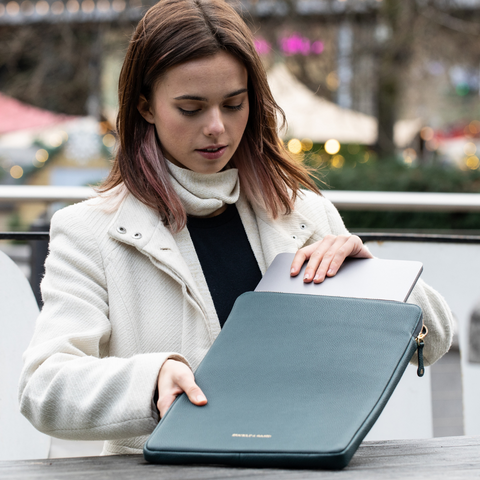 Woman taking a laptop out of a Buckle and Band luxury leather laptop case