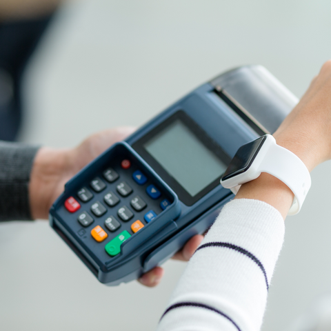 A person paying with their Apple Watch against a chip and pin device