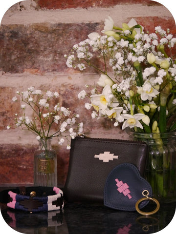 bracelet, purse, keyring and flowers in front of a brick wall