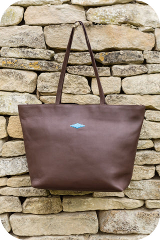 brown leather bag hanging by a wall