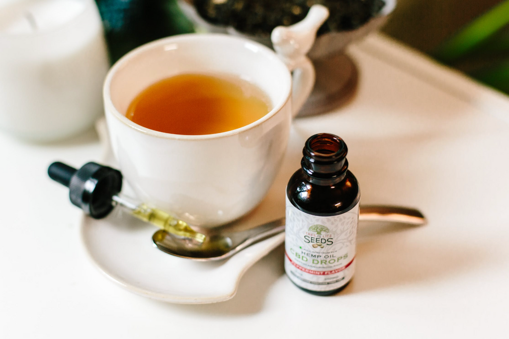 CBD product with a dropper next to a cup of tea