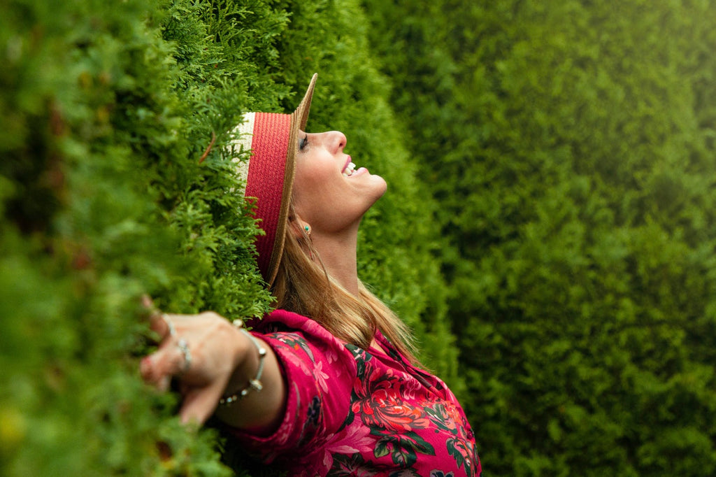 Woman happy leaning against a green wall of plants