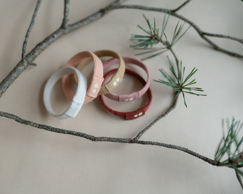 KOOSHOO Festive Hair Ties laid out on a surface surrounded by pine branches