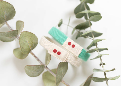 Plastic-free, organic cotton Kooshoo hair ties laying among green branches.