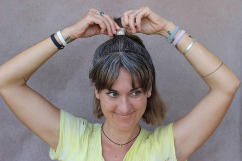 A woman with grey hair pulls her ponytail on top of her head with KOOSHOO Silver hairties