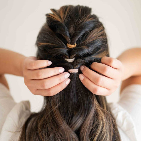 KOOSHOO plastic-free mini hair ties stacked in braid with hands pulling braid tight
