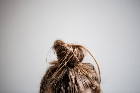 girl with brown hair up in messy top knot bun with plastic-free hair tie 