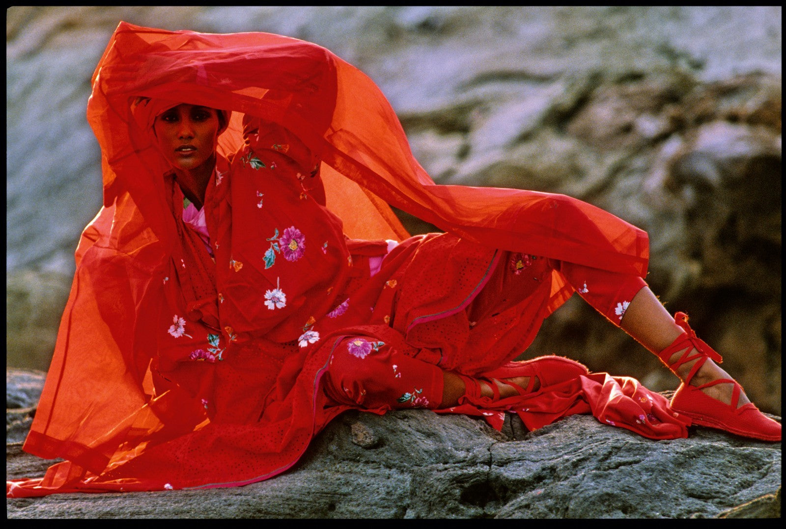 Hans Feurer Kenzo 1983 model in red dress sitting on rocks with veil covering her face