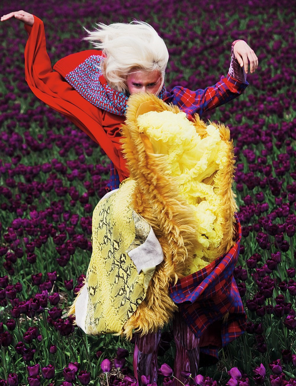 Viviane Sassen Dazed Magazine female model with blonde hair in dynamic pose wearing purple tartan and faux fur in field of purple tulips