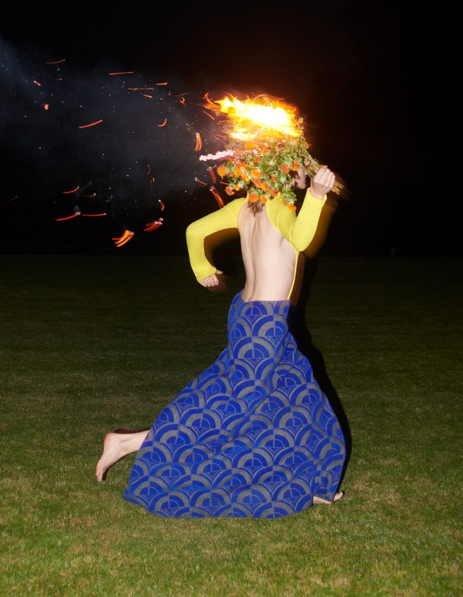 Image  by Johnny Dufort of Woman running at night wearing a blue skirt and holding a flaming bouquet