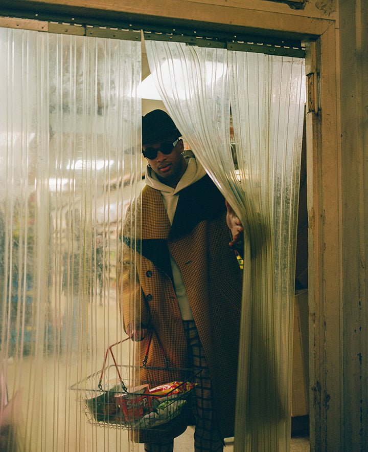 Jorum Studio Winter Campaign model peeks through plastic curtain