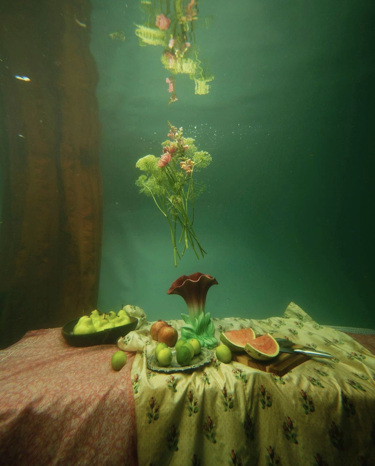 Underwater still life with floating flowers and fruits