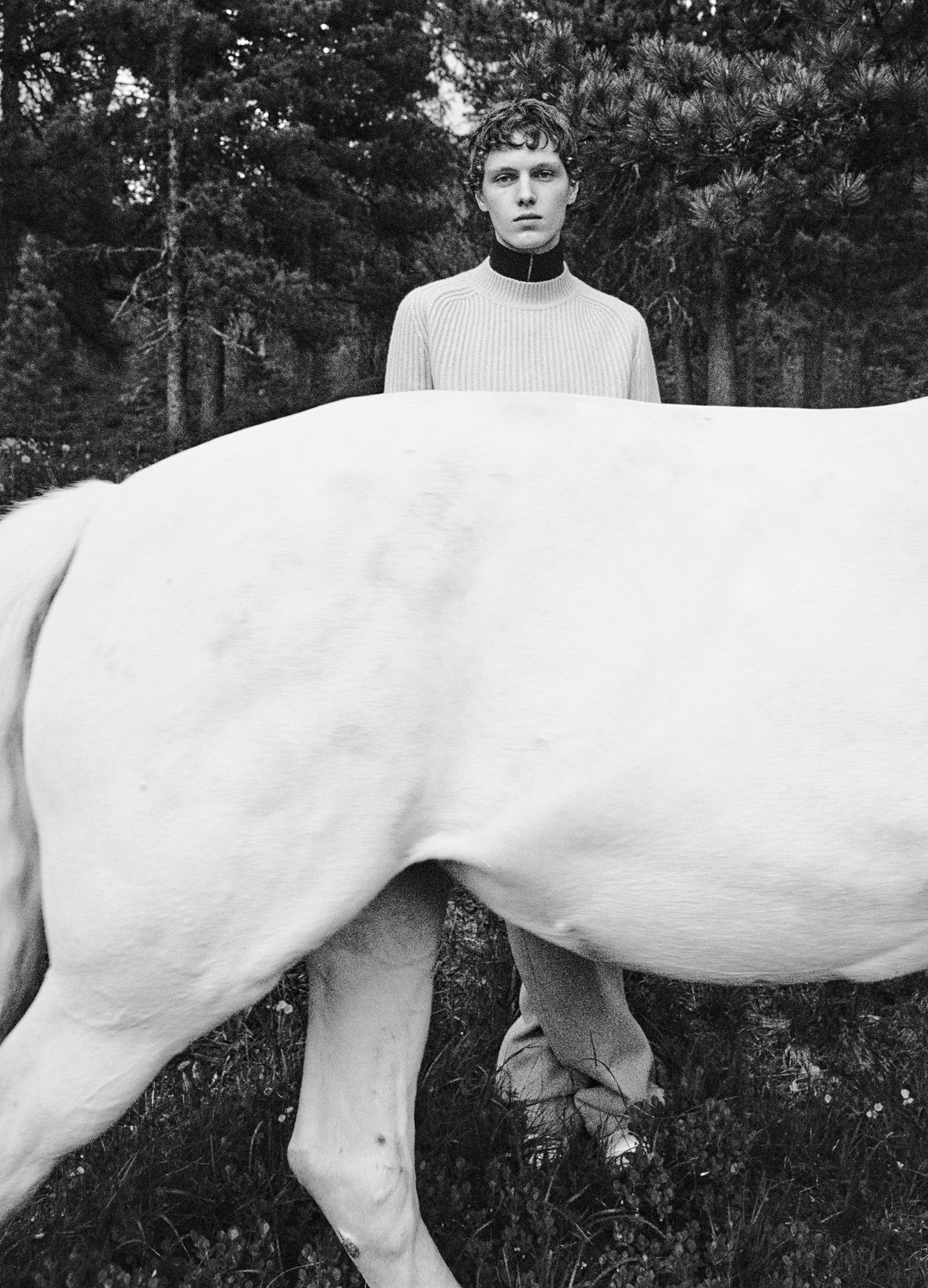 Black and white photograph Jil Sander campaign male model standing behind white horse
