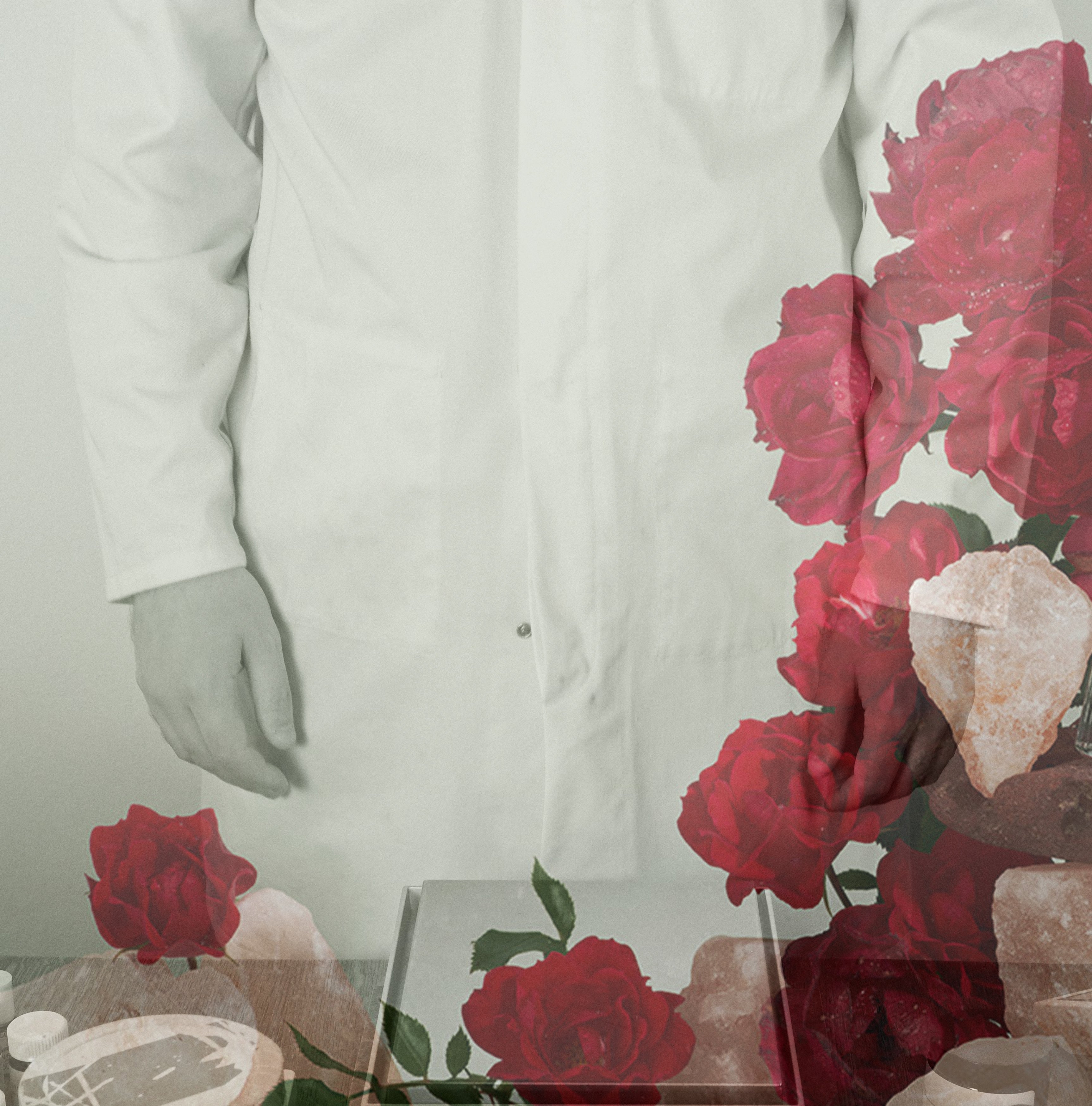 Perfumer standing with scales wearing white lab coat, image overlaid with roses
