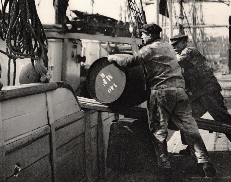 Old photograph of French seafarers rolling barrels onto ship