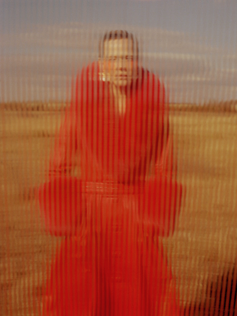 Woman in red coat through reeded glass