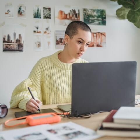 Creative entrepreneur sat working, looking at her laptop