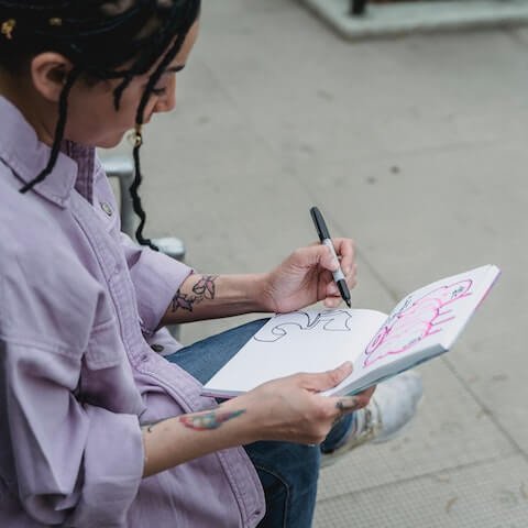 Introvert female creative entrepreneur sketching in a notebook
