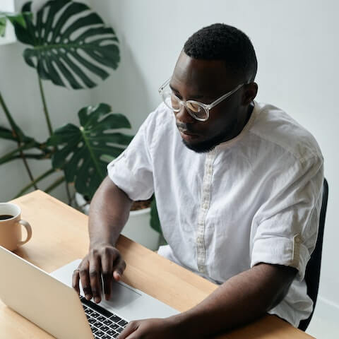 Male, creative entrepreneur sat at a desk working on his laptop