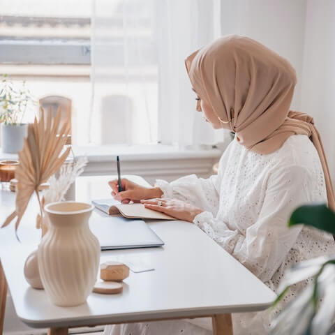 Muslim creative entrepreneur writing in her journal