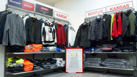 Arbeitskleidung der Marke Kansas ist gut sortiert auf Kleiderstangen aufgehängt