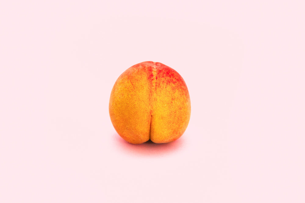 A peach on a light pink background