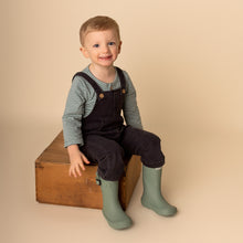 Load image into Gallery viewer, toddler sitting wearing green striped long sleeved shirt, dark denim overalls and green rain boots
