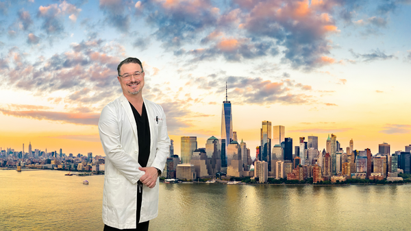 Smiling Dr. Schulman standing in front of new york city skyline with sunsetting