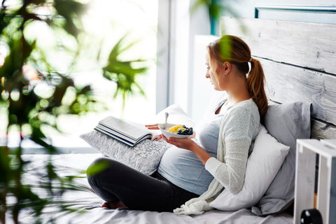 Pregnant woman reading a book at bedroom