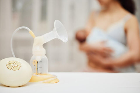 Breast pump with breast milk against the background of a mother holding child