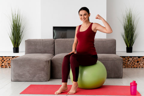 Front view young pregnant woman using a fitness ball