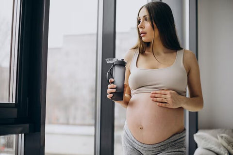 Pregnant Women drinking holding a water bottle in her hand