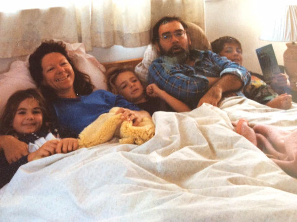 a young family tucked into one big bed with three children in the 90s