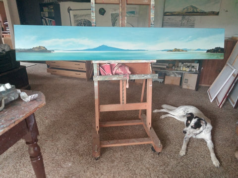 Artist studio with a long landscape oil painting on easel with australian cattle dog on the ground