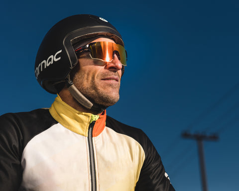 a cycling man looking at the distance wearing Torege sports sunglasses with PC lenses