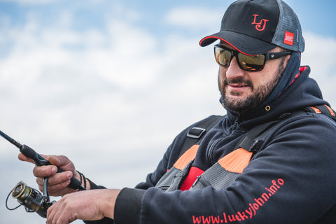 a man angler sitting on a fishing boat holding a fishing rod wearing Torege polarized fishing sunglasses