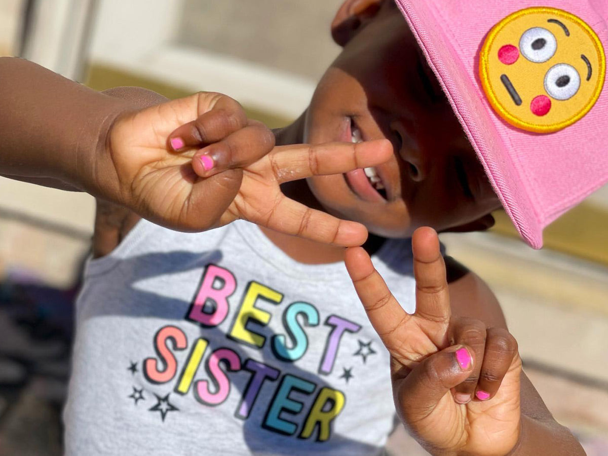 Young girl giving the peace sign while wearing a 3D Xpressions hat