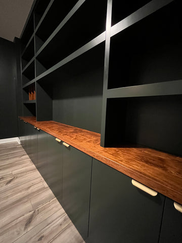 Dark green home office storage built-in with open shelving and closed cabinets