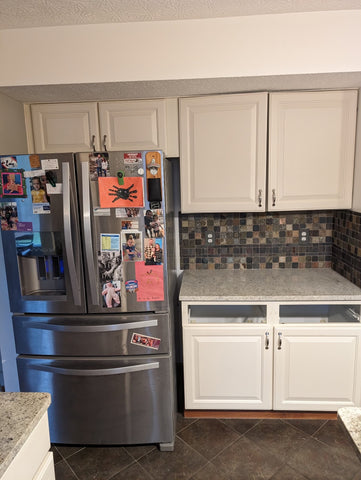 Von Lehmden kitchen before photo of white cabinets, stone backsplash and fridge.