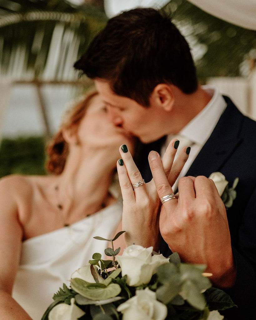 bride and groom kissing while showing off their rings