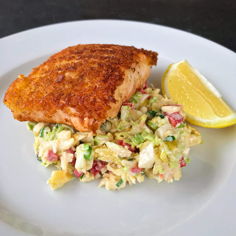 breaded salmon with pimento cheese slaw and lemon on a white plate