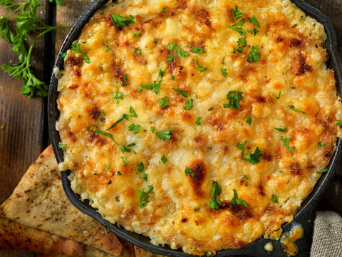 warm creamy crab and artichoke dip on a baking pan with fresh baguette slices