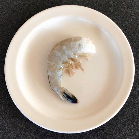 shell on raw shrimp on a white circular plate