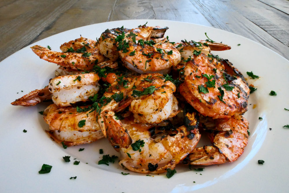grilled shell on cajun shrimp sprinkled with Italian parsley on a white plate