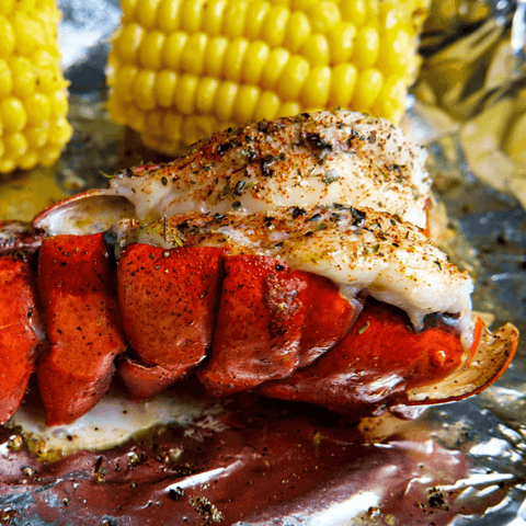 grilled lobster tail on tin foil with corn in the background